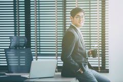 Homme d'affaires travaillant sur l'ordinateur portable dans le bureau, tenant une tasse de café image stock Homme d'affaires travaillant sur l'ordinateur portable dans le bureau, tenant une tasse de café image stock