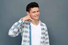 Homme d'isolement sur la position libre de style de mur gris regardant le geste d'appel d'apparence de caméra heureux images stock Homme d'isolement sur la position libre de style de mur gris regardant le geste d'appel d'apparence de caméra heureux images stock