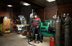 Homme dans le garage, avec le soudage à gaz brûlant de flamme Photographie stock Homme dans le garage, avec le soudage à gaz brûlant de flamme Photographie stock