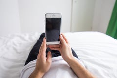 Homme dans son lit à la maison regardant le téléphone portable photo stock Homme dans son lit à la maison regardant le téléphone portable photo stock