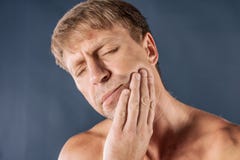 homme déprimé triste en douleur tenant sa joue Portrait d'un homme sur le fond bleu Expression du visage d'émotion sentiments et image libre de droits homme déprimé triste en douleur tenant sa joue Portrait d'un homme sur le fond bleu Expression du visage d'émotion sentiments et image libre de droits
