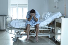 Homme désespéré s'asseyant d'hôpital seul de lit à s triste et désolé image stock Homme désespéré s'asseyant d'hôpital seul de lit à s triste et désolé image stock