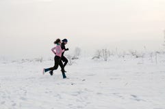 Homme et femme courant sur la neige photographie stock Homme et femme courant sur la neige photographie stock