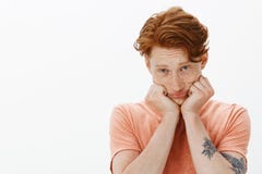 Homme européen roux mignon avec des taches de rousseur sur le visage, la tête de penchement sur des mains et regarder avec fixeme photographie stock Homme européen roux mignon avec des taches de rousseur sur le visage, la tête de penchement sur des mains et regarder avec fixeme photographie stock