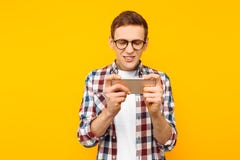 Homme jouant le téléphone sur un fond jaune image stock Homme jouant le téléphone sur un fond jaune image stock