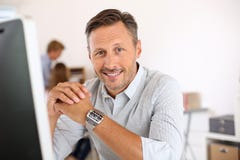 Homme mûr de sourire s'asseyant dans le bureau image libre de droits Homme mûr de sourire s'asseyant dans le bureau image libre de droits