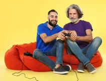 Homme m?r et type jouant des jeux vid?o avec des contr?leurs image libre de droits Homme m?r et type jouant des jeux vid?o avec des contr?leurs image libre de droits