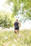 Homme sportif courant en bas du champ par jour ensoleillé photo libre de droits Homme sportif courant en bas du champ par jour ensoleillé photo libre de droits