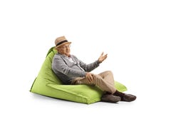 Homme supérieur avec l'expression de visage se reposant sur un fauteuil de sac à haricots et faisant des gestes avec la main photos libres de droits Homme supérieur avec l'expression de visage se reposant sur un fauteuil de sac à haricots et faisant des gestes avec la main photos libres de droits