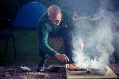 Homme supérieur faisant cuire sur un barbecue Image stock Homme supérieur faisant cuire sur un barbecue Image stock