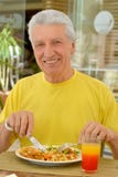 Homme supérieur heureux prenant le petit déjeuner Photographie stock Homme supérieur heureux prenant le petit déjeuner Photographie stock