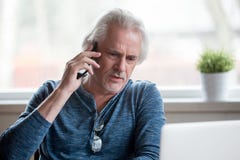 Homme supérieur mécontent parlant au téléphone portable photographie stock Homme supérieur mécontent parlant au téléphone portable photographie stock