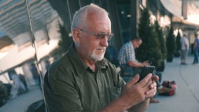 Homme supérieur utilisant l'extérieur de smartphone sur le terminal d'aéroport clips vidéos Homme supérieur utilisant l'extérieur de smartphone sur le terminal d'aéroport clips vidéos