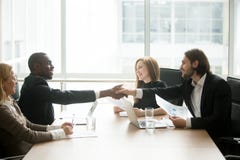 Hommes d'affaires multiraciaux dans la poignée de main de costumes à l'équipe exécutive o images libres de droits Hommes d'affaires multiraciaux dans la poignée de main de costumes à l'équipe exécutive o images libres de droits