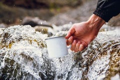 Hommes de touristes portant une tasse en métal dans la perspective des rivières brouillées image libre de droits Hommes de touristes portant une tasse en métal dans la perspective des rivières brouillées image libre de droits