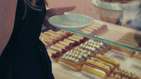 Hon köparen väljer smaskigt Ung attraktiv flicka, kvinnabuys i coffee shop eller bakelser, kakor, kaka, makron A lager videofilmer Hon köparen väljer smaskigt Ung attraktiv flicka, kvinnabuys i coffee shop eller bakelser, kakor, kaka, makron A lager videofilmer