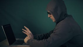 Hoody man coding. Profile side view of white man sitting at table and typing at laptop computer. Hacker in glasses and stock video footage Hoody man coding. Profile side view of white man sitting at table and typing at laptop computer. Hacker in glasses and stock video footage