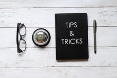 Hoogste die mening van oogglazen, ringsklok, pen en notitieboekje met UITEINDEN & TRUCS op witte houten achtergrond worden geschr stock afbeeldingen Hoogste die mening van oogglazen, ringsklok, pen en notitieboekje met UITEINDEN & TRUCS op witte houten achtergrond worden geschr stock afbeeldingen
