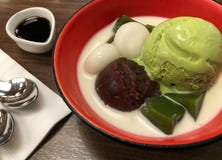 Hoogste mening van groene het roomijslepel van theematcha met rode bonenmochi en melk in rode kom royalty-vrije stock afbeeldingen Hoogste mening van groene het roomijslepel van theematcha met rode bonenmochi en melk in rode kom royalty-vrije stock afbeeldingen
