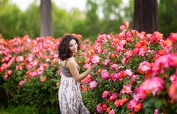 Horisontalstående av den caucasian kvinnan för ung attraktiv brunett nära den enorma rosa rosa busken i en trädgård Le som ser ti royaltyfria foton Horisontalstående av den caucasian kvinnan för ung attraktiv brunett nära den enorma rosa rosa busken i en trädgård Le som ser ti royaltyfria foton