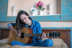 Horyzontalny modniś dziewczyny portret z gitarą akustyczną bawić się na łóżku Fotografia Stock Horyzontalny modniś dziewczyny portret z gitarą akustyczną bawić się na łóżku Fotografia Stock