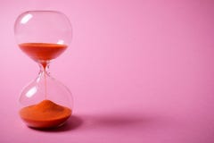 Hourglass with orange sand on pink background. royalty free stock photos Hourglass with orange sand on pink background. royalty free stock photos
