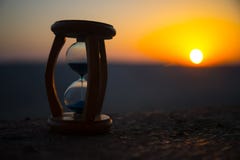 Hourglass Passing Of Time Lapse Clouds. An Hourglass In Front Of A Bright Blue Sky With Puffy White Clouds Passing. Time Concept. Royalty Free Stock Images Hourglass Passing Of Time Lapse Clouds. An Hourglass In Front Of A Bright Blue Sky With Puffy White Clouds Passing. Time Concept. Royalty Free Stock Images