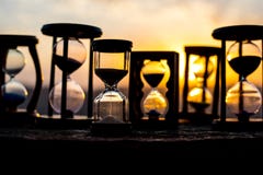 Hourglass Passing Of Time Lapse Clouds. An Hourglass In Front Of A Bright Blue Sky With Puffy White Clouds Passing. Time Concept. Royalty Free Stock Photo Hourglass Passing Of Time Lapse Clouds. An Hourglass In Front Of A Bright Blue Sky With Puffy White Clouds Passing. Time Concept. Royalty Free Stock Photo