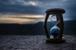 Hourglass Passing Of Time Lapse Clouds. An Hourglass In Front Of A Bright Blue Sky With Puffy White Clouds Passing. Time Concept. Royalty Free Stock Image Hourglass Passing Of Time Lapse Clouds. An Hourglass In Front Of A Bright Blue Sky With Puffy White Clouds Passing. Time Concept. Royalty Free Stock Image