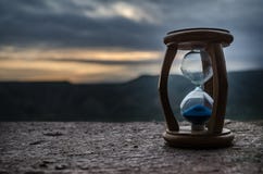 Hourglass Passing Of Time Lapse Clouds. An Hourglass In Front Of A Bright Blue Sky With Puffy White Clouds Passing. Time Concept. Royalty Free Stock Images Hourglass Passing Of Time Lapse Clouds. An Hourglass In Front Of A Bright Blue Sky With Puffy White Clouds Passing. Time Concept. Royalty Free Stock Images