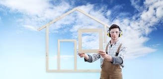 House construction renovation concept handyman carpenter man show the model of a wooden house isolated on blue sky background, stock photography House construction renovation concept handyman carpenter man show the model of a wooden house isolated on blue sky background, stock photography