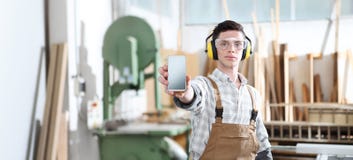 House construction renovation concept handyman carpenter worker man show the mobile phone isolated with the model of a wooden royalty free stock photo House construction renovation concept handyman carpenter worker man show the mobile phone isolated with the model of a wooden royalty free stock photo