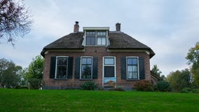 A house in Giethoorn, the Netherlands, photographed on water channels on a fall day, with green grass, and special architecture of stock photo A house in Giethoorn, the Netherlands, photographed on water channels on a fall day, with green grass, and special architecture of stock photo