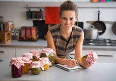 Housewife writing in notepad in kitchen stock images Housewife writing in notepad in kitchen stock images