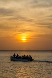 Houten boot met niet identificeerbare mensen en mooie zonsondergang over overzees, Bubaque, Bijagos-eilanden, Guinea-Bissau, Afri stock foto Houten boot met niet identificeerbare mensen en mooie zonsondergang over overzees, Bubaque, Bijagos-eilanden, Guinea-Bissau, Afri stock foto