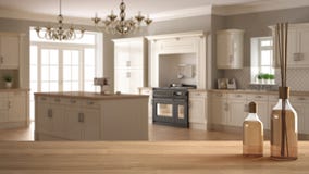 Houten lijstbovenkant of plank met aromatische stokkenflessen over vage klassieke keuken met eiland, witte architectuur binnenlan royalty-vrije stock fotografie Houten lijstbovenkant of plank met aromatische stokkenflessen over vage klassieke keuken met eiland, witte architectuur binnenlan royalty-vrije stock fotografie
