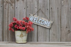 Houten welkom teken met pot van bloemen door houten omheining stock foto Houten welkom teken met pot van bloemen door houten omheining stock foto
