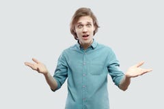 How you did it? Portrait of shocked handsome young man in blue casual shirt standing with raised arms and asking with unbelievable royalty free stock photography How you did it? Portrait of shocked handsome young man in blue casual shirt standing with raised arms and asking with unbelievable royalty free stock photography