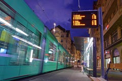Riding public transportation in Basel with fast moving green tram in front of Marktplatz public stop station at night, Switzerland