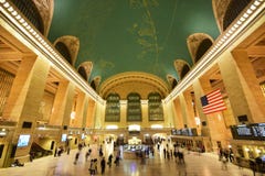 Commuter rail Grand Central Terminal GCT New York with American flag, iconic clock atop information booth, display panel