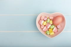 Huevo colorido de Pascua en un plato bajo la forma de corazón con los dulces foto de archivo libre de regalías Huevo colorido de Pascua en un plato bajo la forma de corazón con los dulces foto de archivo libre de regalías