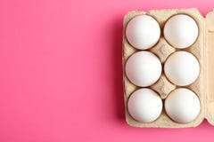 Huevos del pollo en caja del cartón en fondo rosado foto de archivo Huevos del pollo en caja del cartón en fondo rosado foto de archivo