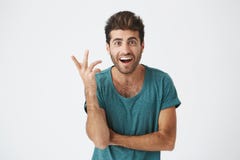 Human face expressions, emotions and feelings. Astonished and surprised bearded young man in blue t-shirt pointing at Stock Photo Human face expressions, emotions and feelings. Astonished and surprised bearded young man in blue t-shirt pointing at Stock Photo