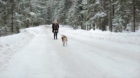 Hundbeaglet kör till och med snön Gulliga unga hipsterpar som har gyckel i vinter, parkerar med deras hund på en ljus dag och lager videofilmer Hundbeaglet kör till och med snön Gulliga unga hipsterpar som har gyckel i vinter, parkerar med deras hund på en ljus dag och lager videofilmer