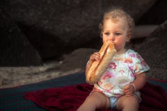 Hungry baby girl eating baguette bread countryside rustic lifestyle copy space Stock Image Hungry baby girl eating baguette bread countryside rustic lifestyle copy space Stock Image