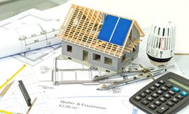 Hus med ett konstruktionsplan och en solpanelplanläggning royaltyfri foto Hus med ett konstruktionsplan och en solpanelplanläggning royaltyfri foto