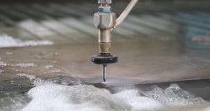 Hydroabrasive high pressure CNC machine is cutting out a shape on a metal sheet.