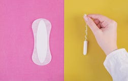 Hygiene care during critical days. Choosing between a tampon and a sanitary pad. Menstrual cycle. The woman holds in hands of a royalty free stock photography Hygiene care during critical days. Choosing between a tampon and a sanitary pad. Menstrual cycle. The woman holds in hands of a royalty free stock photography