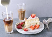 Hälla mjölka in i exponeringsglaset av kaffe, smaklig skiva av sockerkakan med jordgubbar på plattan Kaffetid med den läckra söts arkivbilder Hälla mjölka in i exponeringsglaset av kaffe, smaklig skiva av sockerkakan med jordgubbar på plattan Kaffetid med den läckra söts arkivbilder