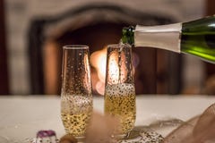 hällande champagne från flaskan in i glass framme av spisen arkivfoto hällande champagne från flaskan in i glass framme av spisen arkivfoto
